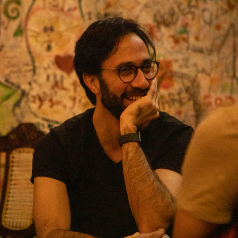 Vikram laughing mid-conversation against a graffiti-covered wall, rendered as a dithered halftone
